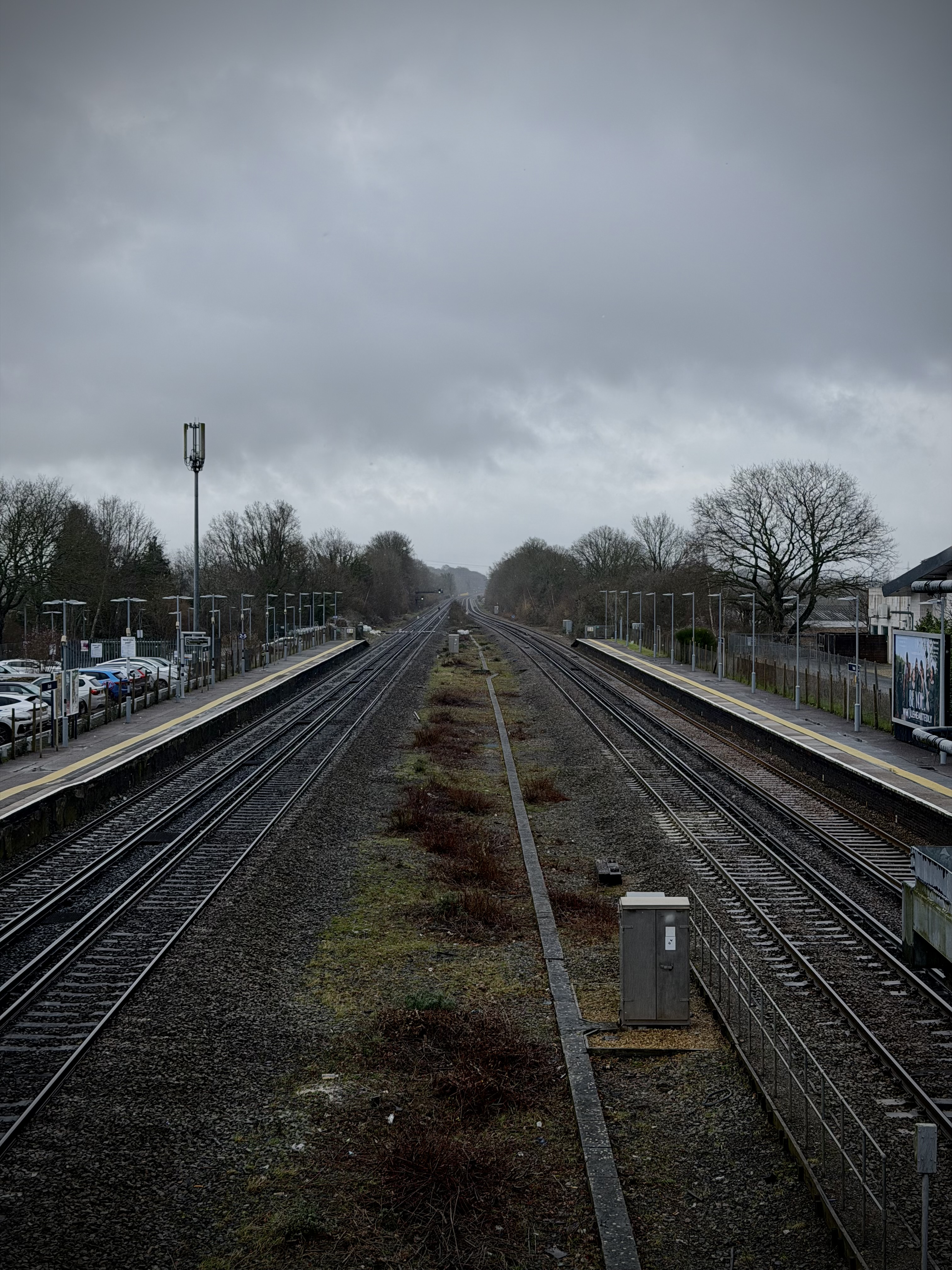 Hook Railway Station showing the four-track layout with two outer platforms for stopping services and two inner fast lines for express trains, under overcast Hampshire sky